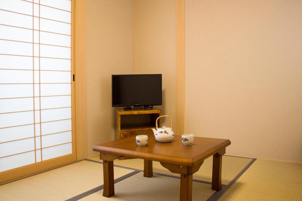 un salon avec une table basse et une télévision dans l'établissement Kamoya Ryokan, à Kyoto