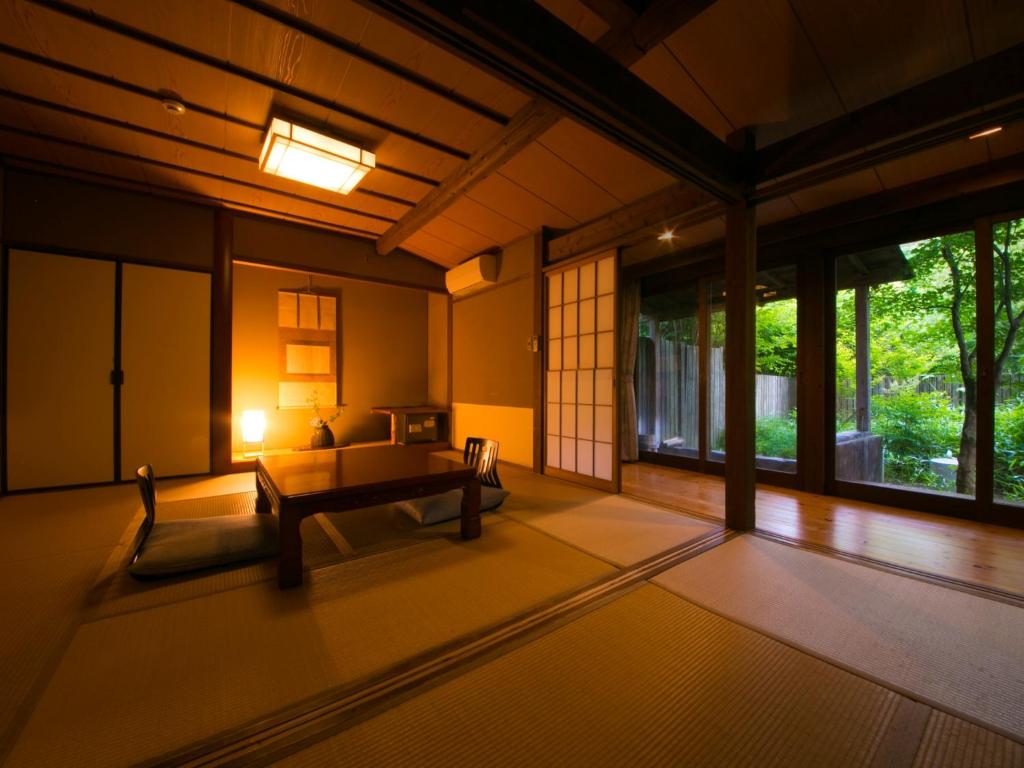 une chambre avec un banc, une table et des fenêtres dans l'établissement Yufuin Gettouan, à Yufu