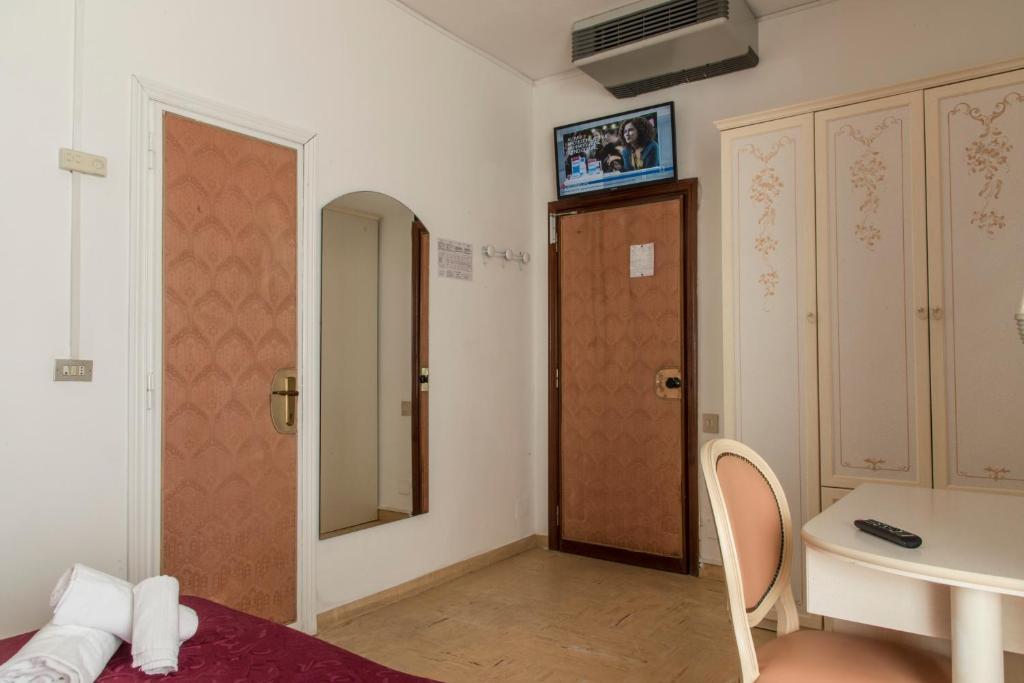 une chambre avec un lit, une table et un miroir dans l'établissement Hotel Baia Marina, à Cattolica