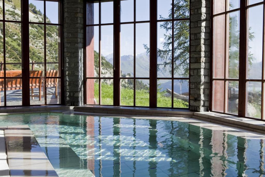 une piscine intérieure avec fenêtres et vue sur les montagnes dans l'établissement appartement de standing Arc 1950, à Bourg-Saint-Maurice