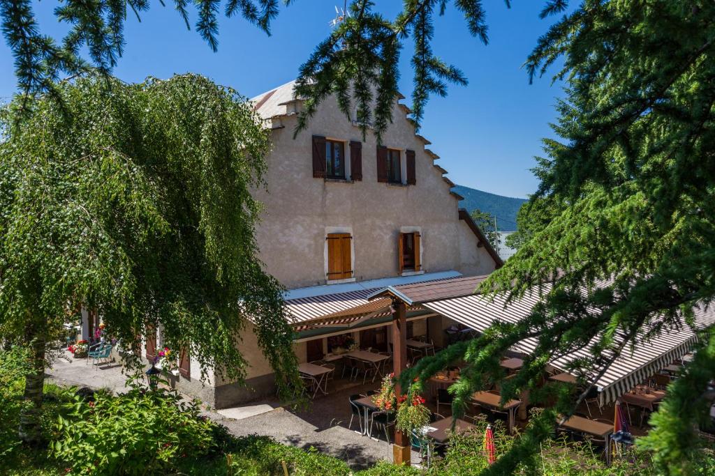 un bâtiment avec des tables et des chaises devant lui dans l'établissement Auberge des Montauds - Hôtel & Restaurant, à Villard-de-Lans