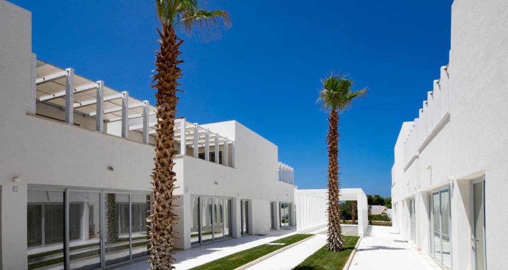 deux palmiers devant un bâtiment blanc dans l'établissement Camarò Favignana, à Favignana