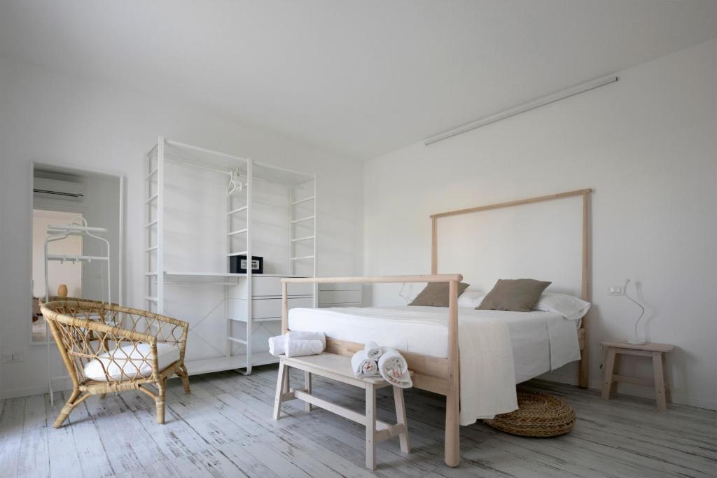 une chambre blanche avec un lit et une chaise dans l'établissement Camarò Favignana, à Favignana