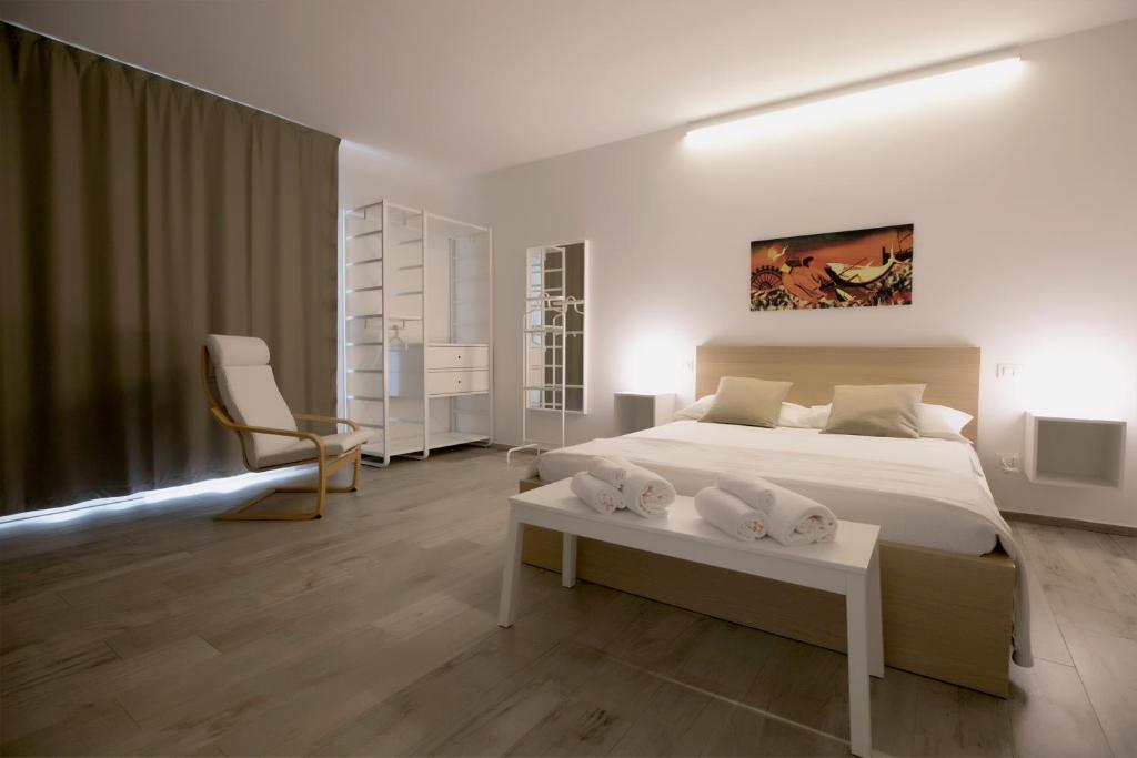 une chambre blanche avec un lit et une chaise dans l'établissement Camarò Favignana, à Favignana