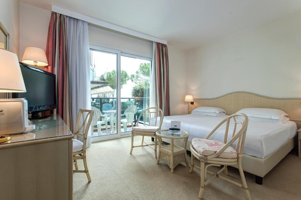 une chambre d'hôtel avec un lit, une table et des chaises dans l'établissement Park Hotel Brasilia, à Lido di Jesolo 77 autres photos