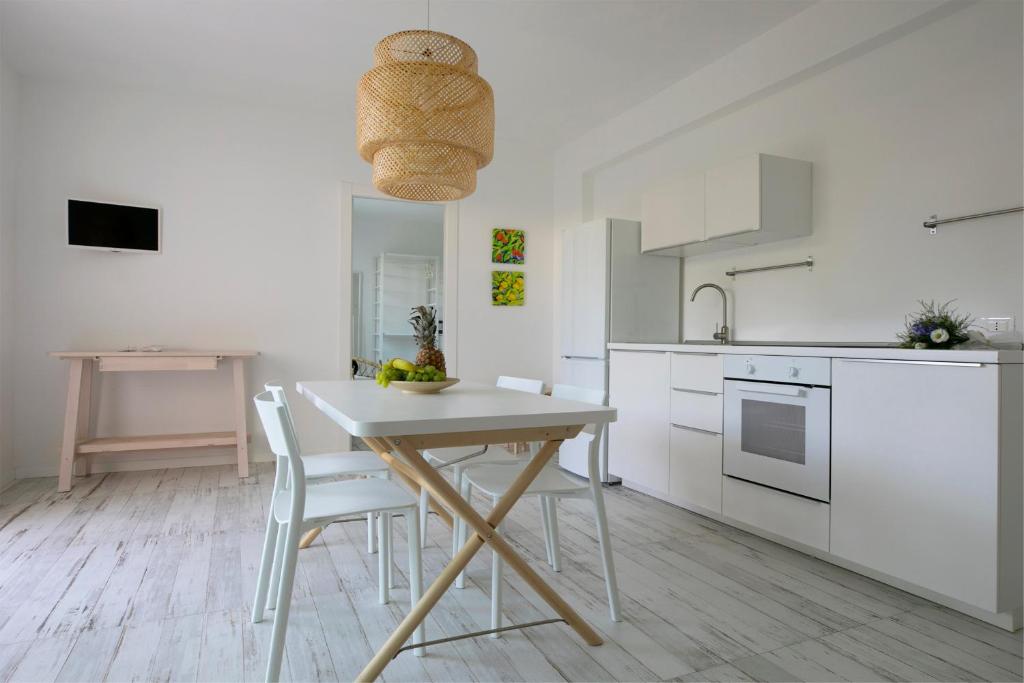 - une cuisine blanche avec une table et des chaises en bois dans l'établissement Camarò Favignana, à Favignana
