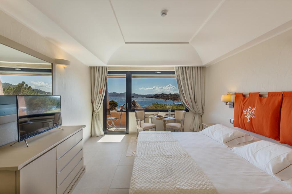 une chambre d'hôtel avec un grand lit et une télévision dans l'établissement Hotel Cala Lunga, à La Maddalena