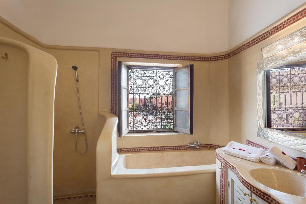 une salle de bain avec une baignoire, un lavabo et une fenêtre dans l'établissement Riad les Rêves d'Amélie, à Marrakech
