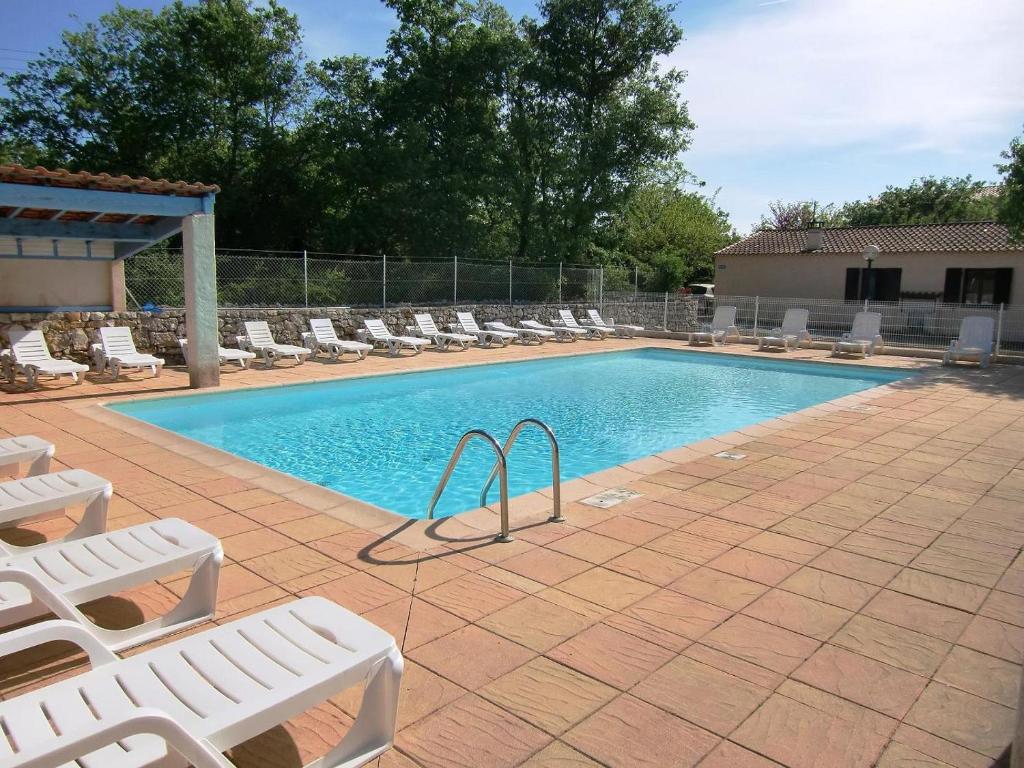 une piscine avec des chaises longues blanches et une piscine dans l'établissement Village de gites Le Frigoulet, à Balazuc