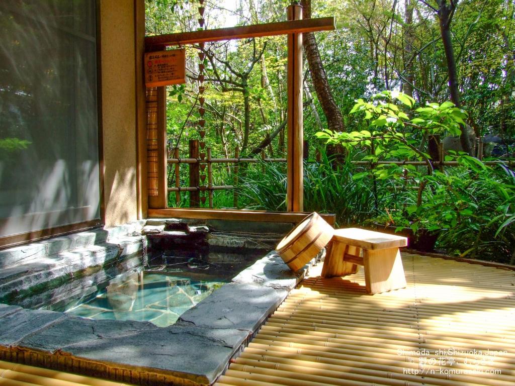 une piscine avec un banc à côté d'une maison dans l'établissement Nonohanatei komurasaki, à Shimoda