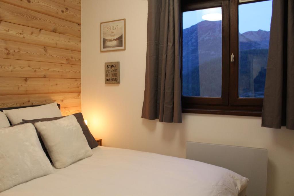 une chambre avec un lit blanc avec une fenêtre dans l'établissement La Chamoisiere Montgenevre, à Montgenèvre