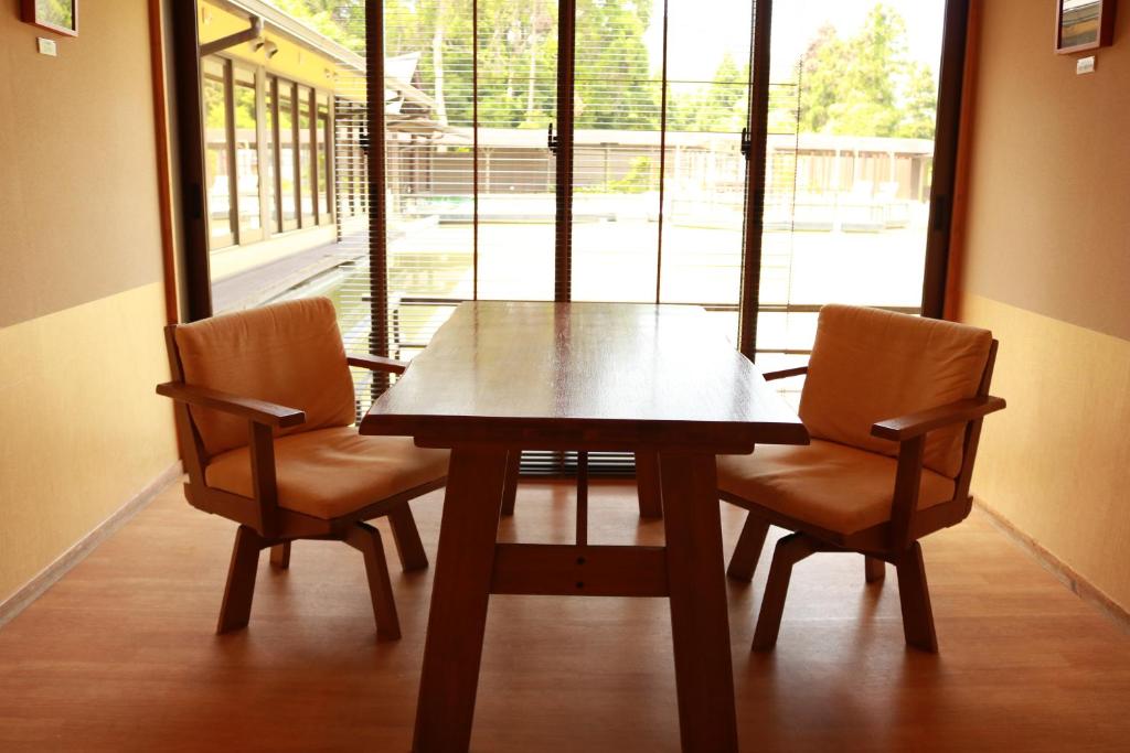 une table à manger avec deux chaises et une grande fenêtre dans l'établissement Onsensui Pool & Fufu Rotenburo no Hanareyado Yurian, à Ibusuki