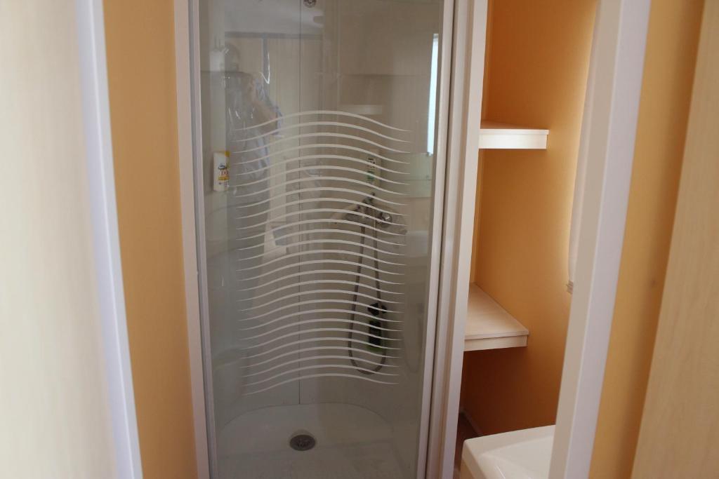 La salle de bains est pourvue d'une douche en verre et de toilettes. dans l'établissement Camping du Pontis, à Verteillac