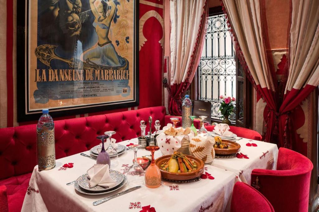 une salle à manger avec une table, des chaises rouges et une photo dans l'établissement Riad Hikaya, à Marrakech