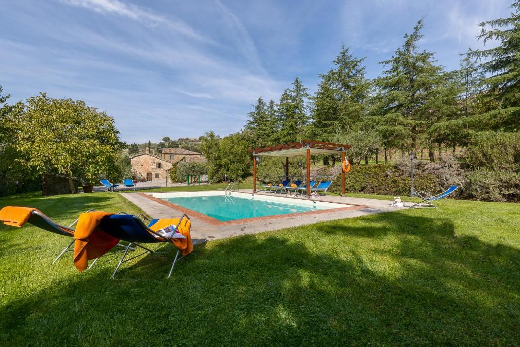 une cour avec une piscine entourée de chaises dans l'herbe dans l'établissement Villa Fontocchio, à Cortone