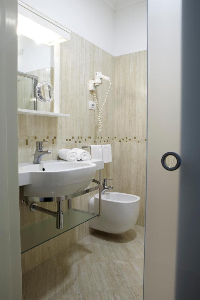 une salle de bain avec un lavabo, des toilettes et un miroir dans l'établissement Ruhl Beach Hotel & Suites, à Lido di Jesolo