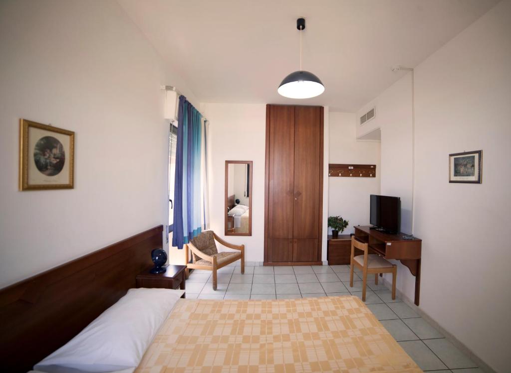 une chambre avec un lit, un bureau et une télévision dans l'établissement Hotel Nettuno, à Soverato Marina