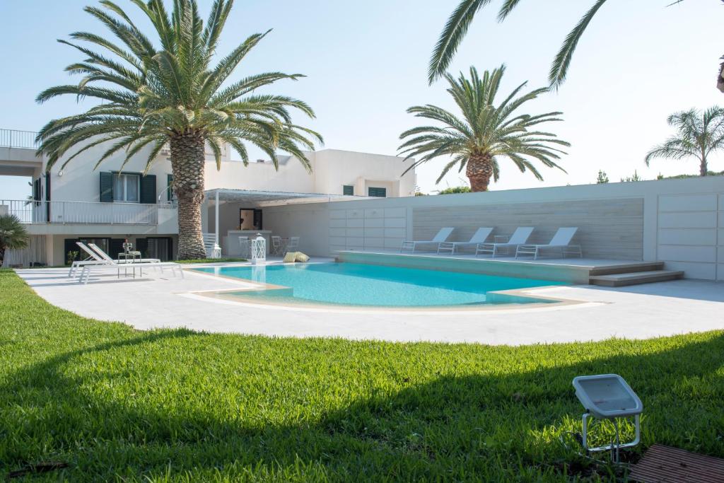 une maison avec une piscine et des palmiers dans l'établissement Villa Vulcano, à Marina di Ragusa