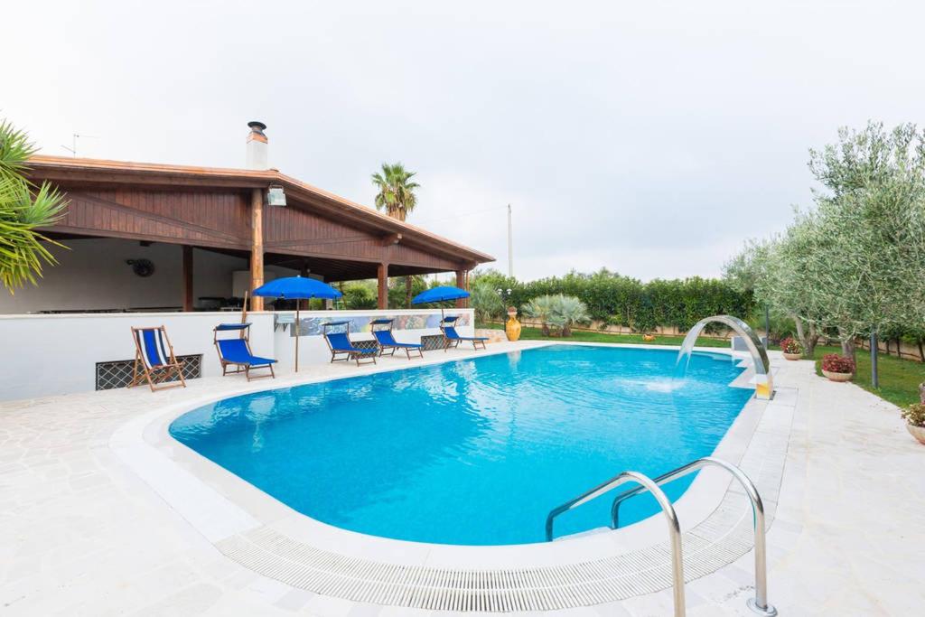 une grande piscine avec des chaises et des parasols bleus dans l'établissement Villa Abbracciavento, à Martina Franca