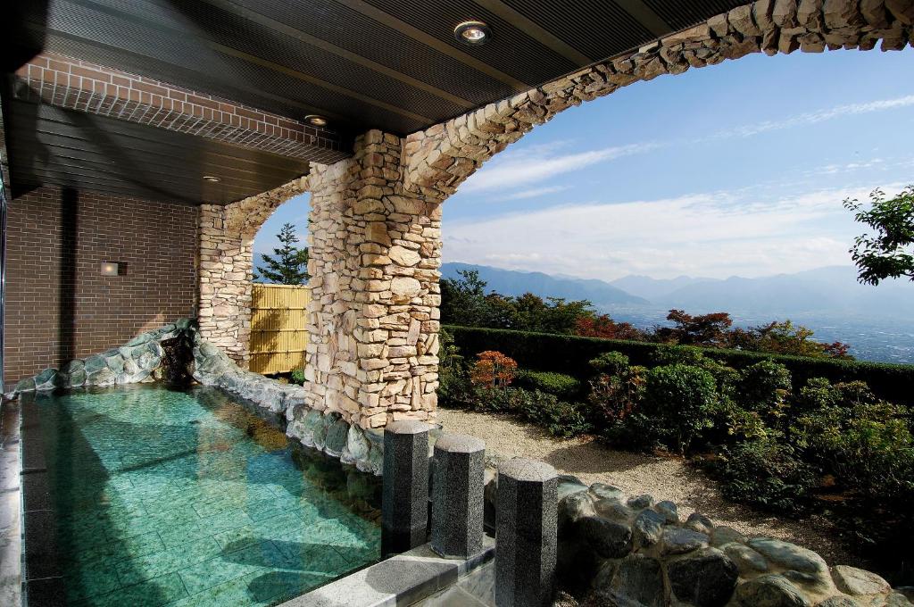 - une piscine dans une maison dotée d'un mur en pierre dans l'établissement Fruit Park Fujiya Hotel, à Yamanashi
