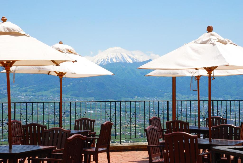un restaurant avec des tables, des parasols et une montagne dans l'établissement Fruit Park Fujiya Hotel, à Yamanashi