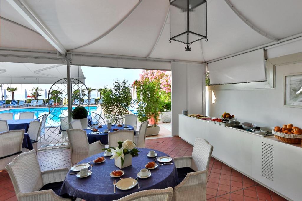 une salle à manger avec une table et des chaises et une piscine dans l'établissement Hotel Plaza Esplanade, à Lido di Jesolo