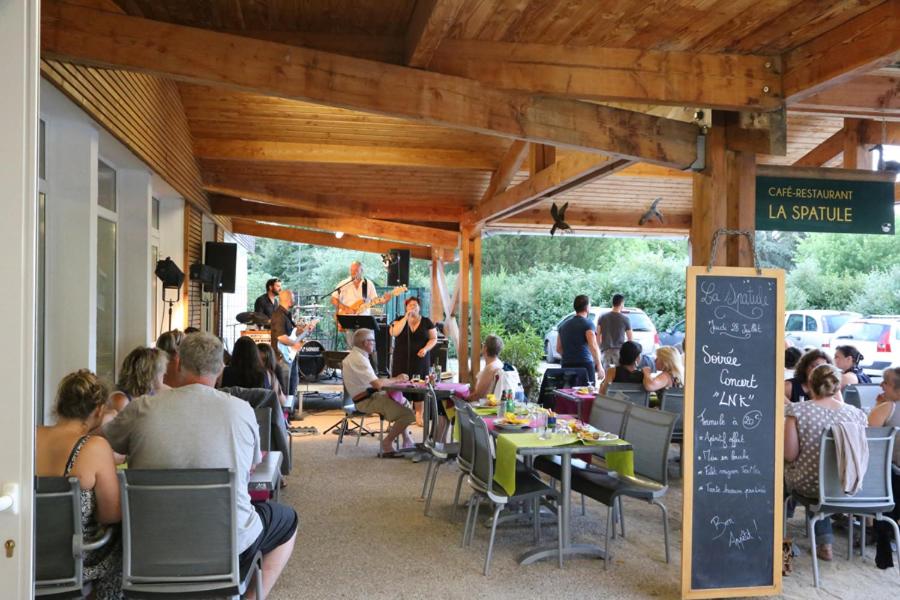 un groupe de personnes assises à des tables dans un restaurant dans l'établissement Camping le Nid du Parc, à Villars-les-Dombes