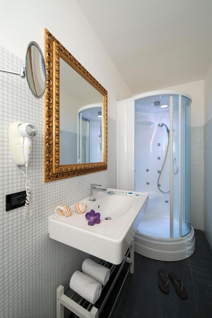 une salle de bain avec un lavabo, une douche et un miroir dans l'établissement Nice Hotel Bibione, à Bibione