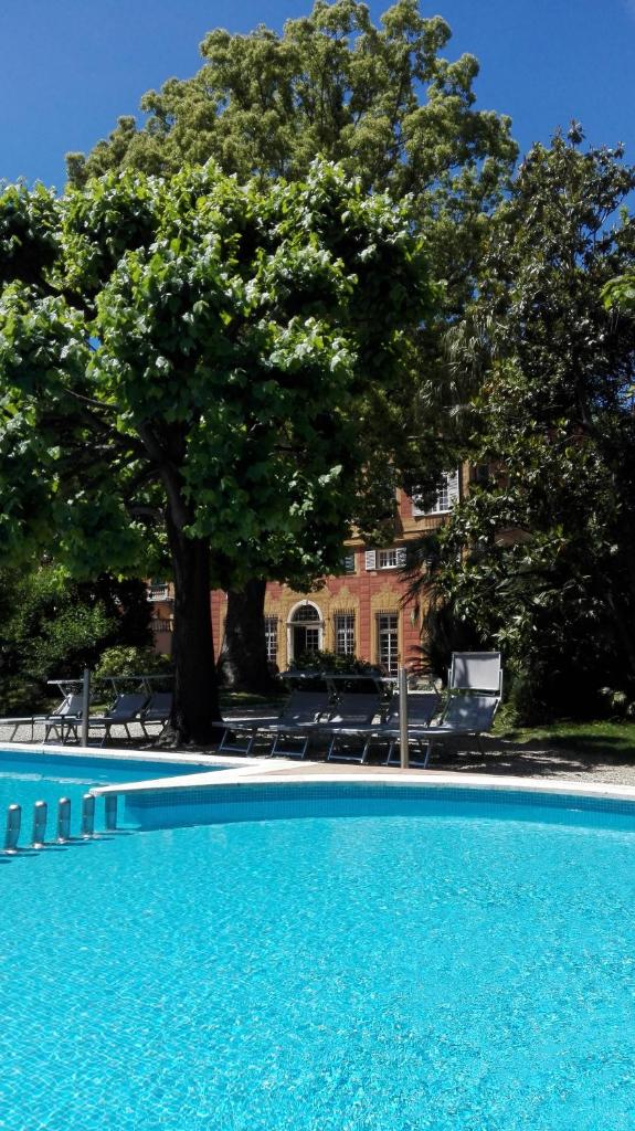 une grande piscine bleue avec un arbre en arrière-plan dans l'établissement Grand Hotel Villa Balbi, à Sestri Levante