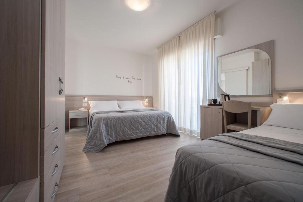 une chambre d'hôtel avec deux lits et un miroir dans l'établissement Hotel Anny, à Lido di Jesolo