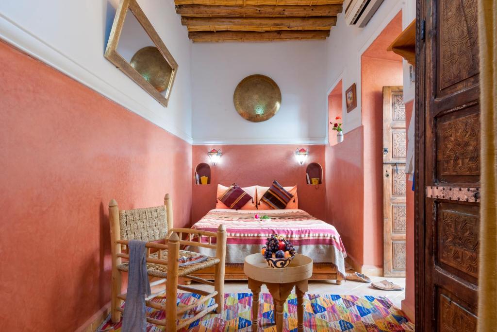 - une chambre avec des murs orange et un lit avec une table dans l'établissement Riad Dar Jdati, à Marrakech