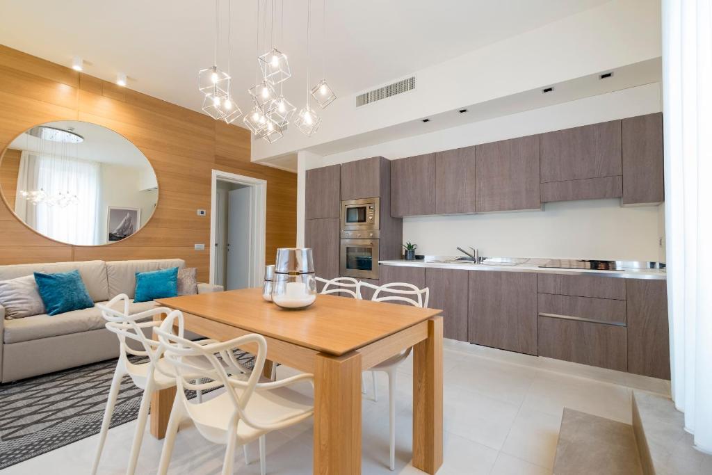 Il dispose d'une cuisine et d'un salon avec une table et des chaises en bois. dans l'établissement Metropol Ceccarini Suite - Luxury apartments, à Riccione