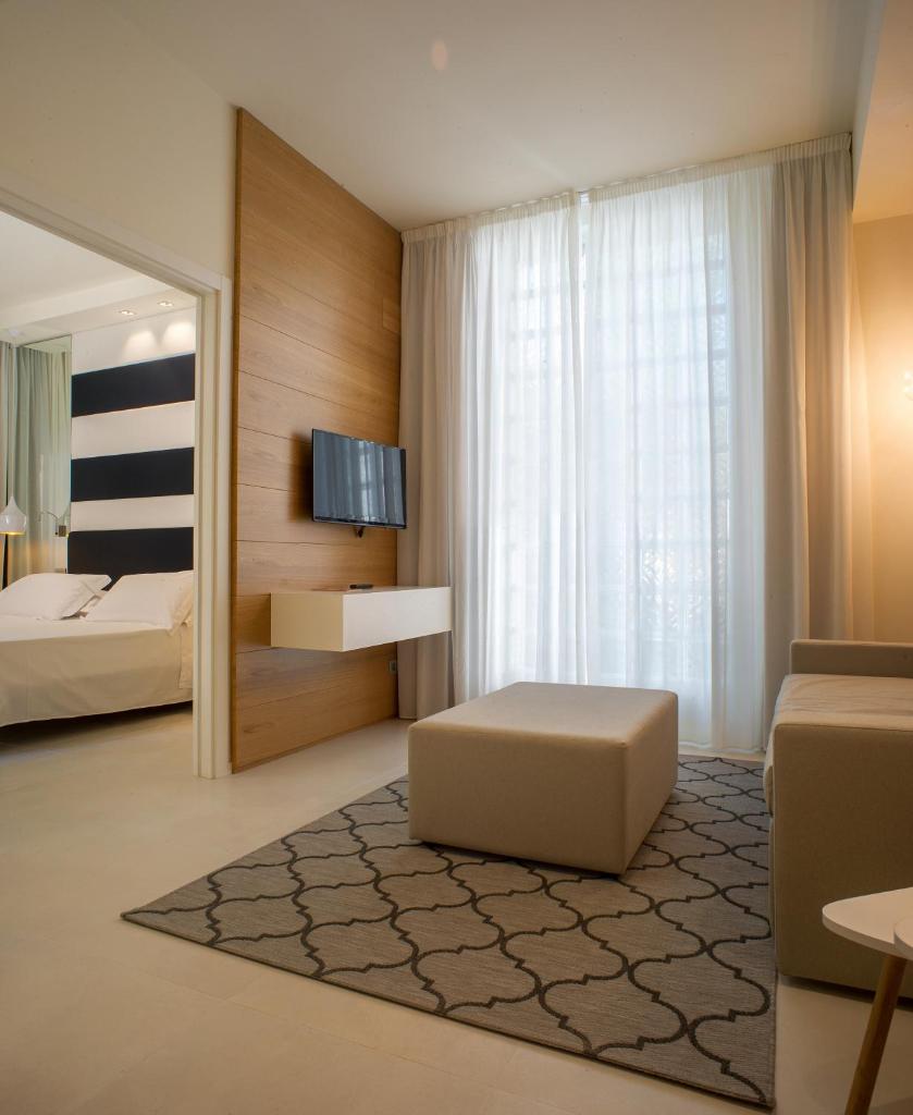 une chambre avec un lit, un canapé et un miroir dans l'établissement Metropol Ceccarini Suite - Luxury apartments, à Riccione