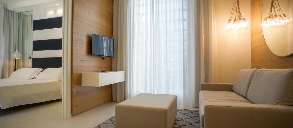 une chambre avec un lit, un canapé et un miroir dans l'établissement Metropol Ceccarini Suite - Luxury apartments, à Riccione
