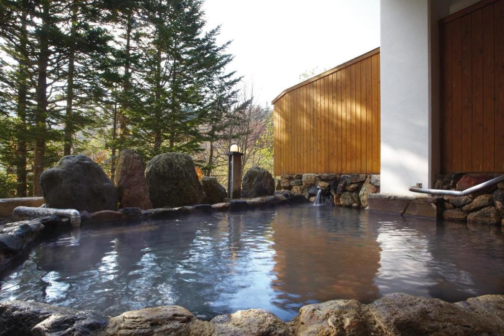 un bassin d'eau dans une cour avec des rochers dans l'établissement Kurplaza Pirika, à Hanaishi