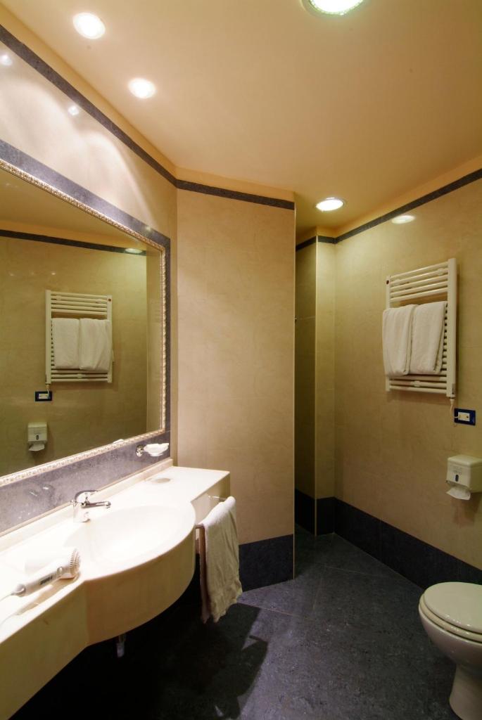 une salle de bain avec un lavabo, des toilettes et un miroir dans l'établissement Grand Eurhotel, à Montesilvano