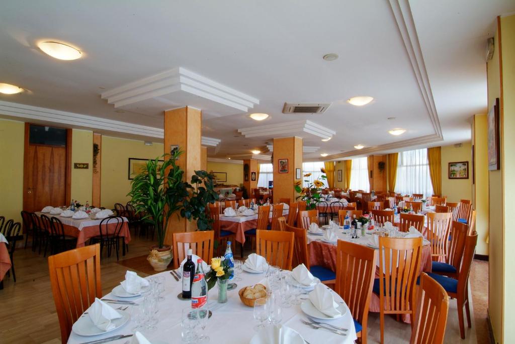 une salle à manger avec des tables et des chaises blanches dans l'établissement Grand Eurhotel, à Montesilvano