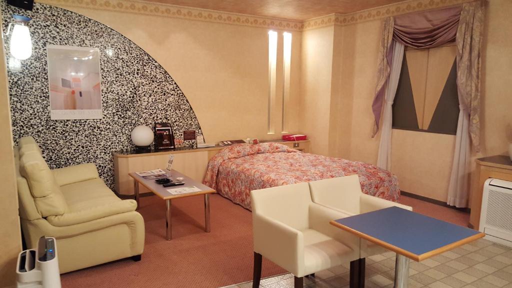 une chambre avec un lit, une chaise et une table dans l'établissement Hotel Elegance (Love Hotel), à Karatsu