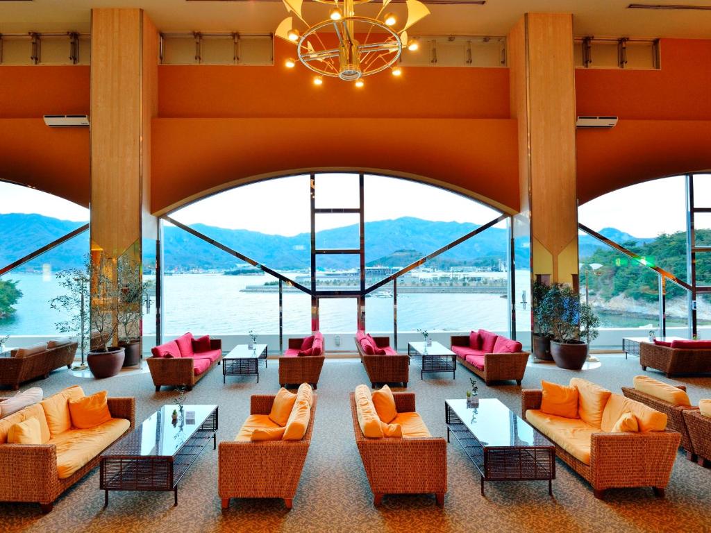 un grand hall avec des canapés, des tables et des fenêtres dans l'établissement Bay Resort Hotel Shodoshima, à Shodoshima