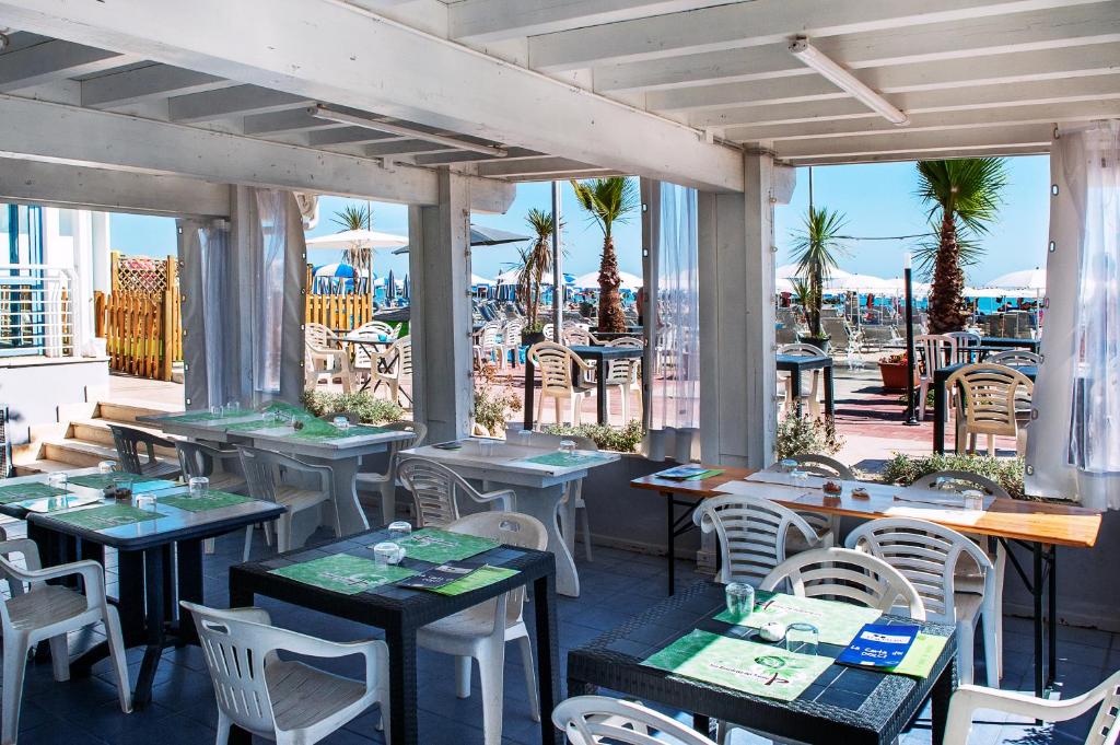 un restaurant avec tables et chaises et vue sur la plage dans l'établissement Hotel Villa Corallo, à San Benedetto del Tronto