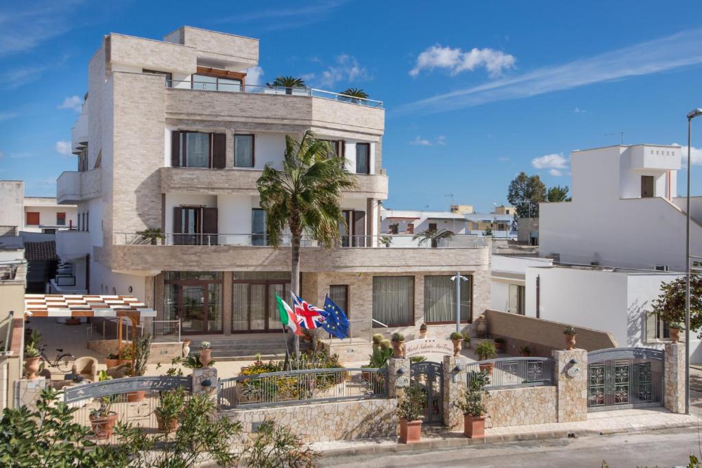un bâtiment avec deux drapeaux devant lui dans l'établissement Hotel Salento Mirfran, à Torre San Giovanni