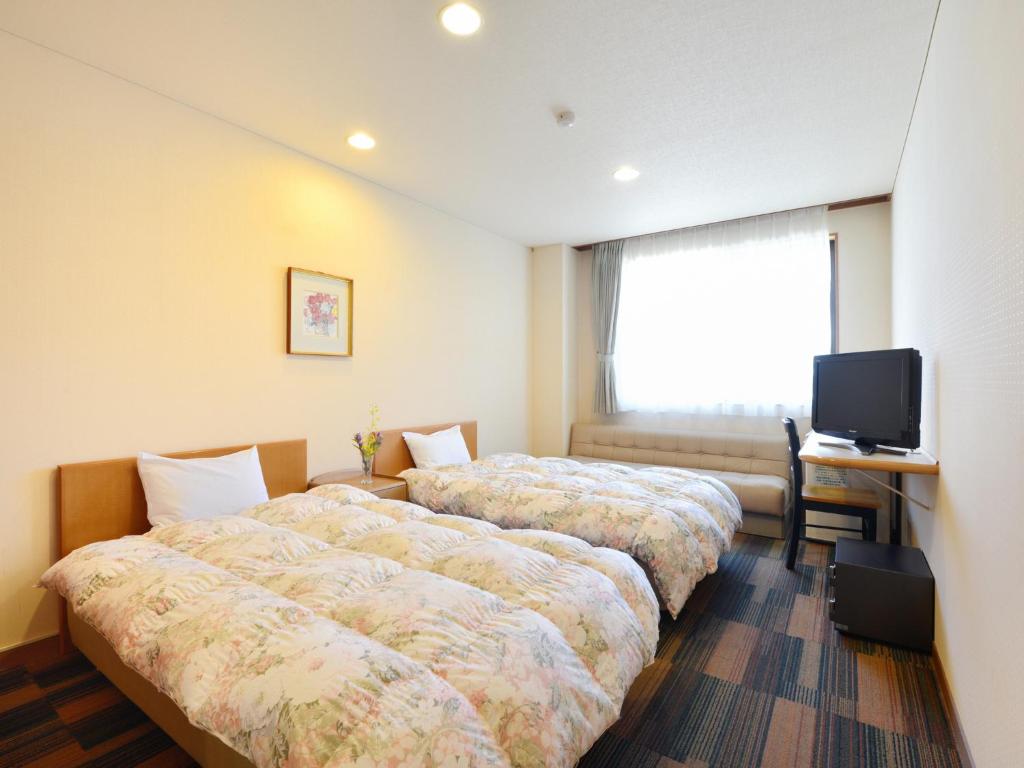 une chambre d'hôtel avec deux lits et une télévision dans l'établissement Hotel Wellness Notoji, à Hakui