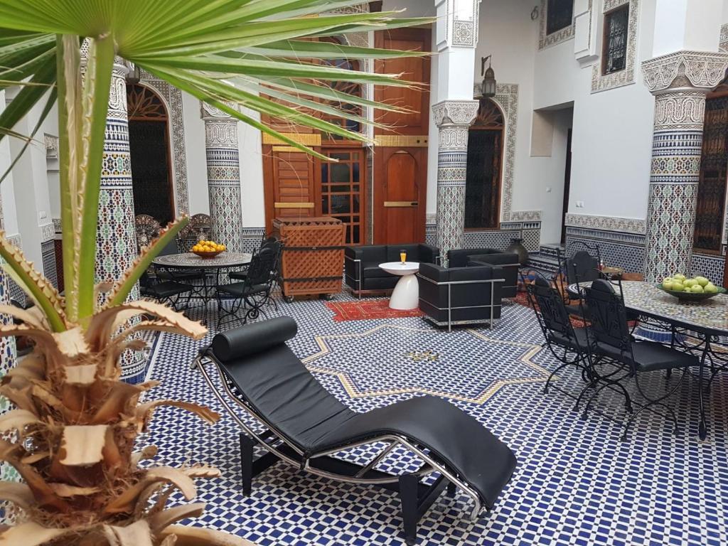 un hall avec des chaises noires et un palmier dans l'établissement Riad Soleil d'Or, à Fès