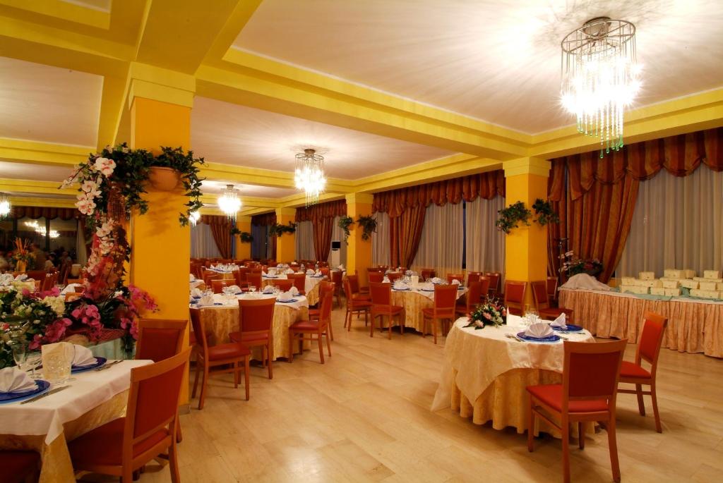 une salle à manger avec tables et chaises et un lustre dans l'établissement Grand Eurhotel, à Montesilvano 43 autres photos