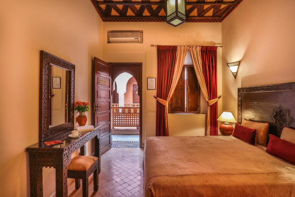 une chambre avec un lit, une table et un miroir dans l'établissement Riad & Spa Bahia Salam, à Marrakech