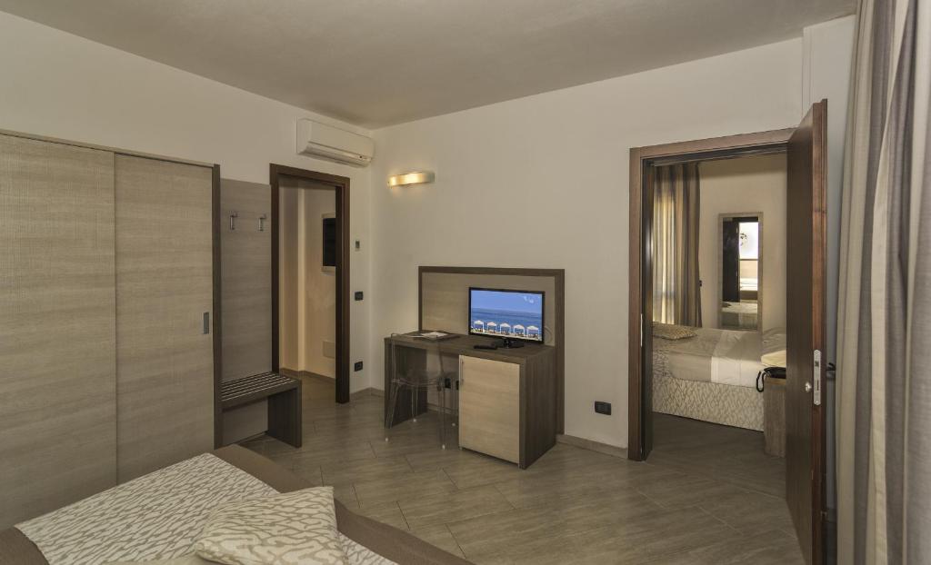 un salon avec une télévision et une chambre dans l'établissement Hotel Lido Inn, à Lido di Camaiore