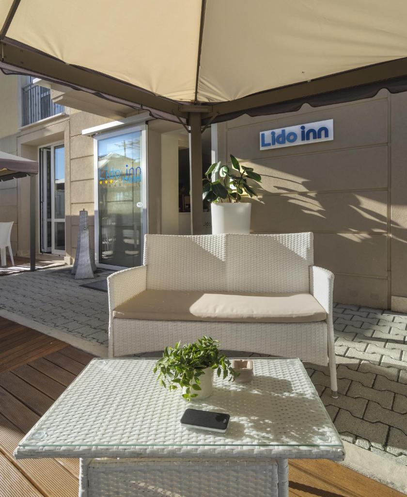 une terrasse avec une table, un canapé et un parasol dans l'établissement Hotel Lido Inn, à Lido di Camaiore
