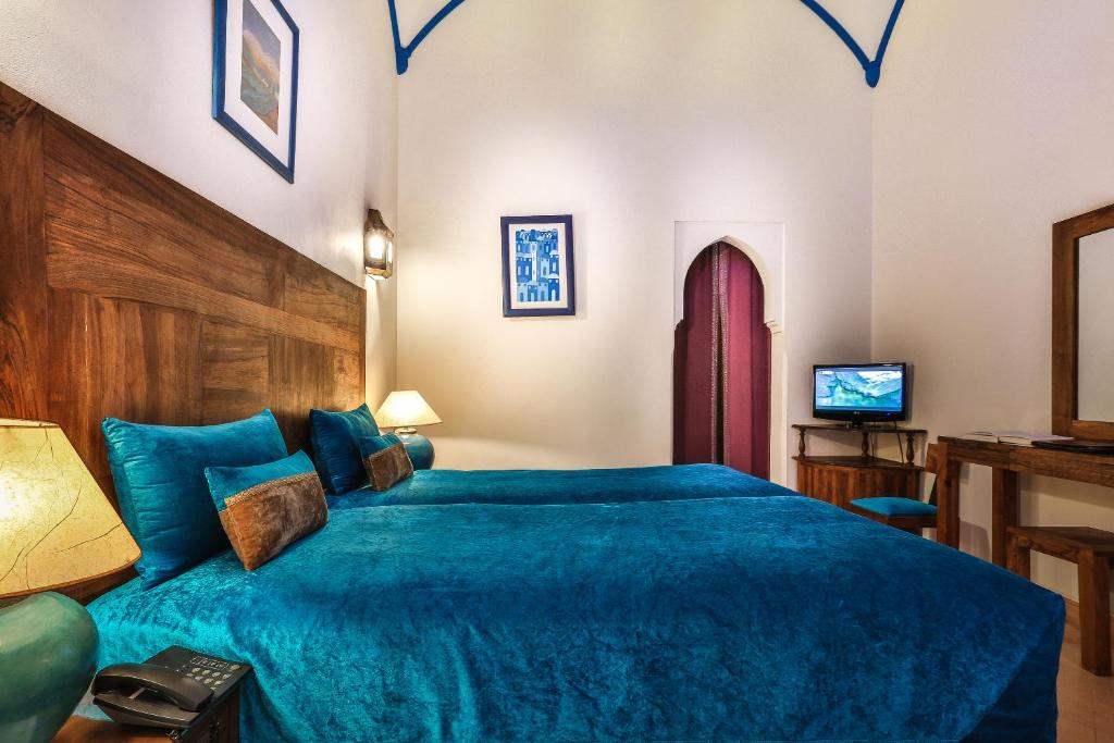 - une chambre avec un lit bleu et une télévision dans l'établissement Riad & Spa Bahia Salam, à Marrakech