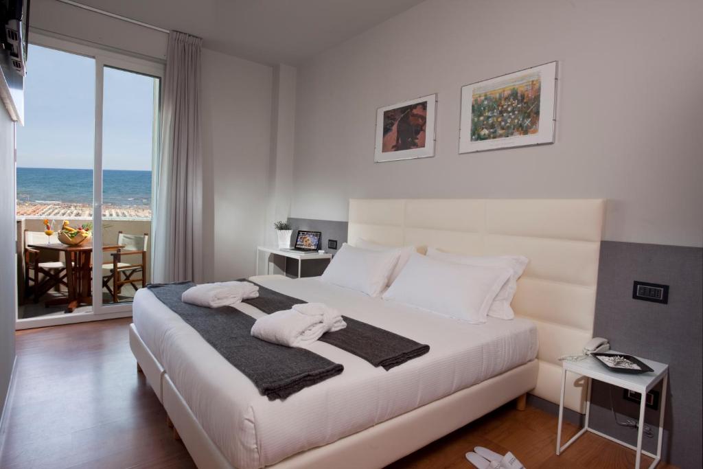 une chambre avec un lit blanc avec vue sur l'océan dans l'établissement Hotel Ascot & Spa, à Rimini