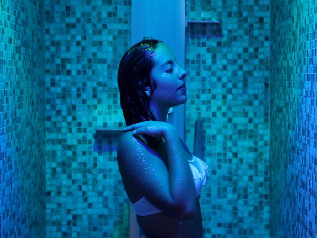 une femme debout devant un miroir de salle de bain dans l'établissement Hotel Villa, à Bisceglie